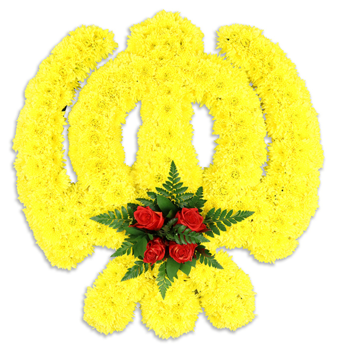 This image presents an eloquent floral interpretation of the Sikh Khanda, meticulously shaped from an abundant layer of bright yellow chrysanthemum heads. The arrangement delineates the emblem's components-the encircling chakram, the upright double-edged khanda and the two crossed kirpans-each curve and angle rendered through dense, uniform clusters of small yellow blooms that impart a plush, cushion-like texture. At the very centre, where the symbol converges, a concentrated grouping of five deep red roses forms a bold, respectful focal point: their lush, layered petals open just enough to suggest warmth without excess, and they are embraced by a spray of dark green fern leaves which provide a crisp, botanical frame. The flowers sit against a plain white field, the simplicity of the backdrop amplifying the vivid yellow and the saturated red while a soft shadow beneath suggests physical depth and careful placement on a tabletop or easel. Up close, the chrysanthemums' delicate petal edges appear almost ruffled, reflecting a soft studio light that makes the yellow glow gently; the roses exhale a subdued fragrance that pairs with the green, fresh notes of the fern. This piece feels equally at home as a ceremonial centrepiece in a gurdwara hall or as a dignified wreath at a memorial service. For residents around Silvertown and the Royal Docks-near the ExCeL precinct and the riverside-the symbolism and craftsmanship will read as a composed, compassionate tribute that honours tradition while speaking plainly in colour and form.