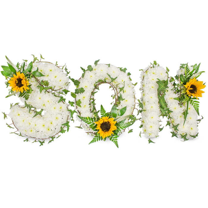 A bespoke, letter-shaped sympathy arrangement clearly spells SON in three robust capitals, set against a pure white studio background that makes textures and colours read with crystal clarity. Each letter is densely covered with hundreds of small white chrysanthemums, their clustered petals forming a soft, pillowed surface that conveys purity and calm. Winding among the chrysanthemums are dark-green ivy vines whose polished, lobed leaves twist and layer to create shadow and structure; lighter fern fronds and additional leafy sprigs rise between the blooms, adding feathery detail and a natural, lively contrast. Three large sunflowers act as focal anchors: one is tucked into the upper-left curve of the S, another is placed at the lower curve of the O where it breaks the circular form, and a third bright bloom adorns the upper-right of the N. The sunflowers' saturated yellow rays and earthy, brown centres bring warmth and a hint of optimism to an otherwise monochrome field, directing attention and offering a visual metaphor for remembrance and light. The overall composition balances texture - the chrysanthemum's plushness, the ivy's gloss, the fern's delicacy and the sunflower's sturdy presence - in a way that reads as both handcrafted and stately. The subtle studio lighting reveals fine details: petal edges, the vein-work of leaves and the layered depth of the letters. As a floral statement intended for funerals or memorial services around Silvertown and nearby North Woolwich Park, it communicates respect, love and the enduring memory of a dearly missed son.